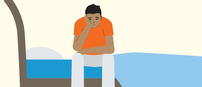 Teen sitting on a bed looking sad